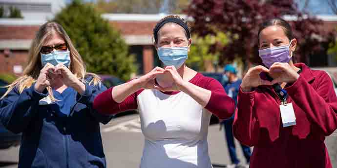 Three healthworkers happy with their hands forming a heart