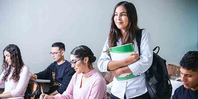 Woman standing up in a class holding books